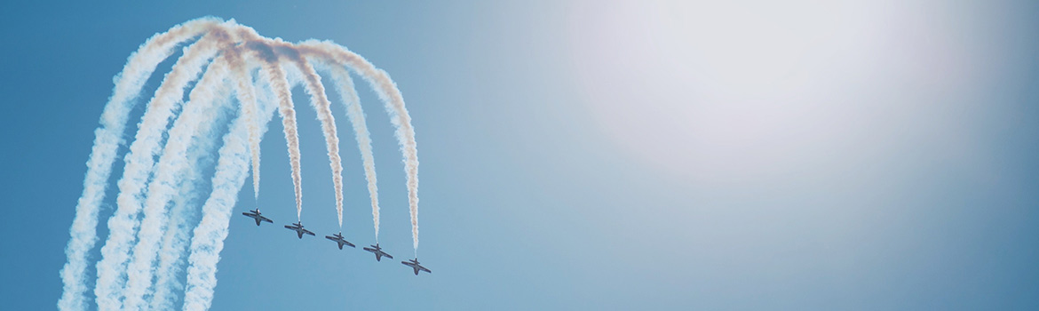 A clear blue sky with a set of planes flying in unison.